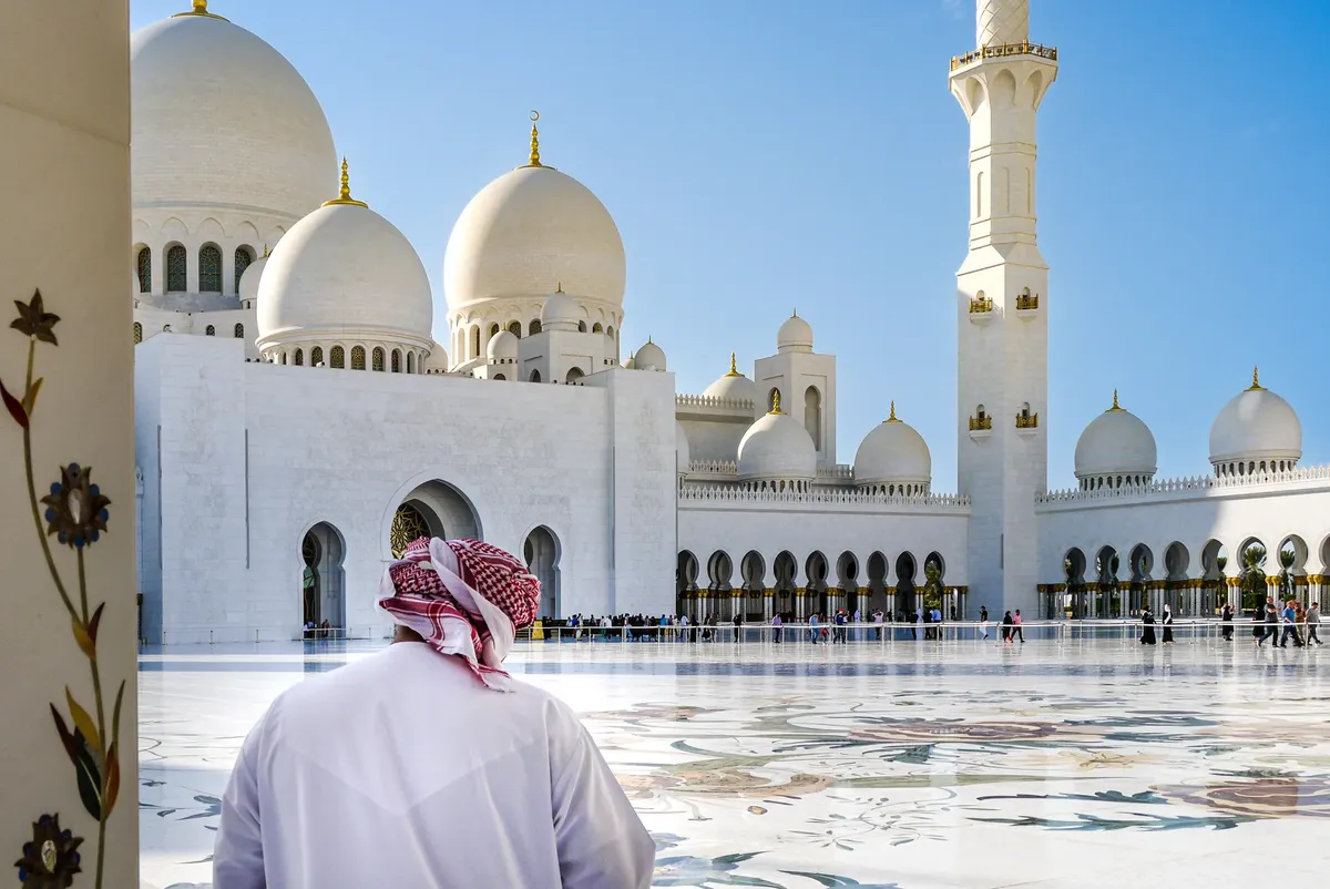 Man in traditional clothing at Sheikh Zayed Grand Mosque courtyard, Abu Dhabi.