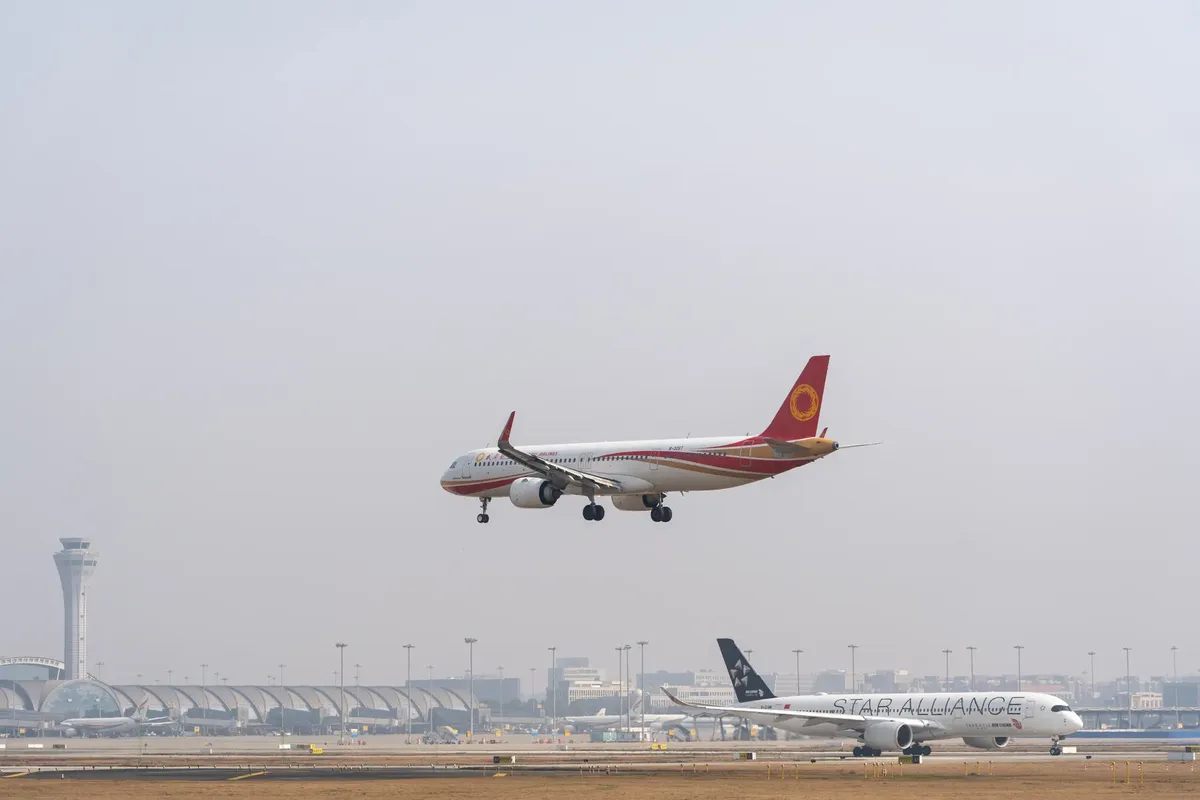 商業航空機がにぎわう国際空港に着陸する様子。空は晴れています。