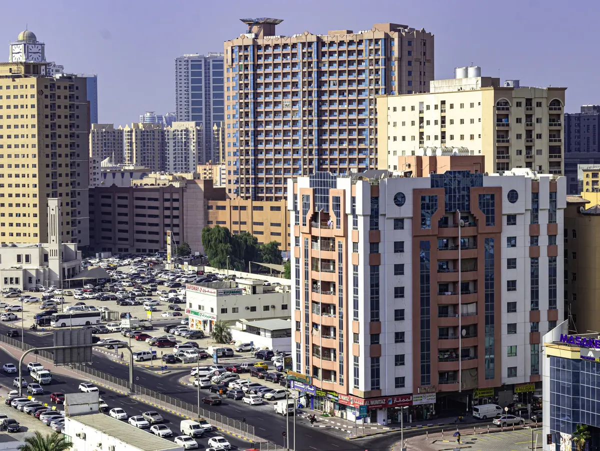 Aerial view of Ajman's urban skyline featuring highrise apartment buildings and busy streets.