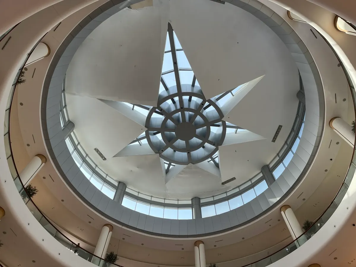 Interior view of Dubai shopping mall with a modern circular skylight featuring geometric design.